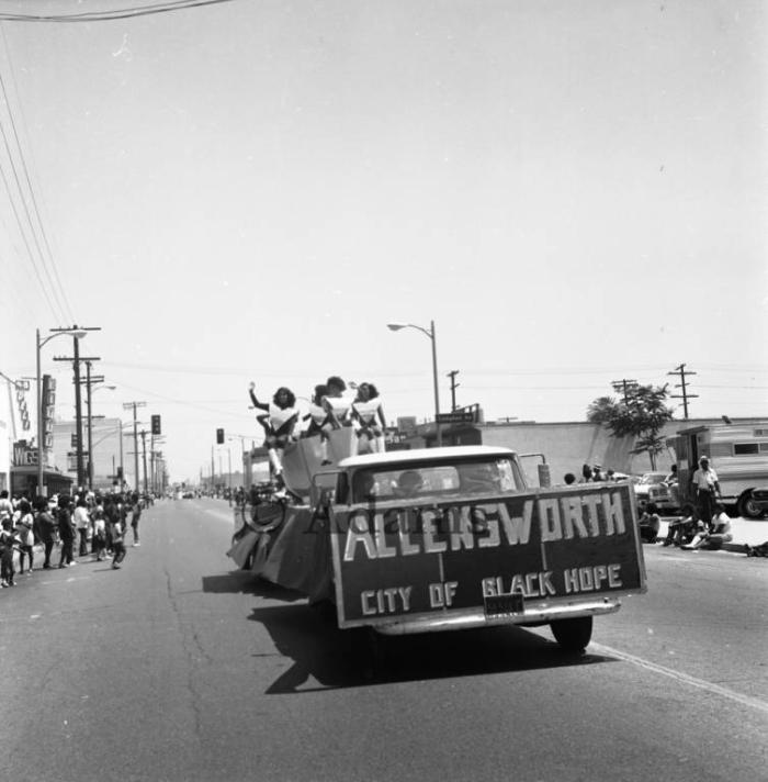 People wave from truck/float with sign for Allensworth, City of Black Hope at the Watts Summer Festival in 1973.  Courtesy of Harry Adams and © Tom & Ethel Bradley Center.