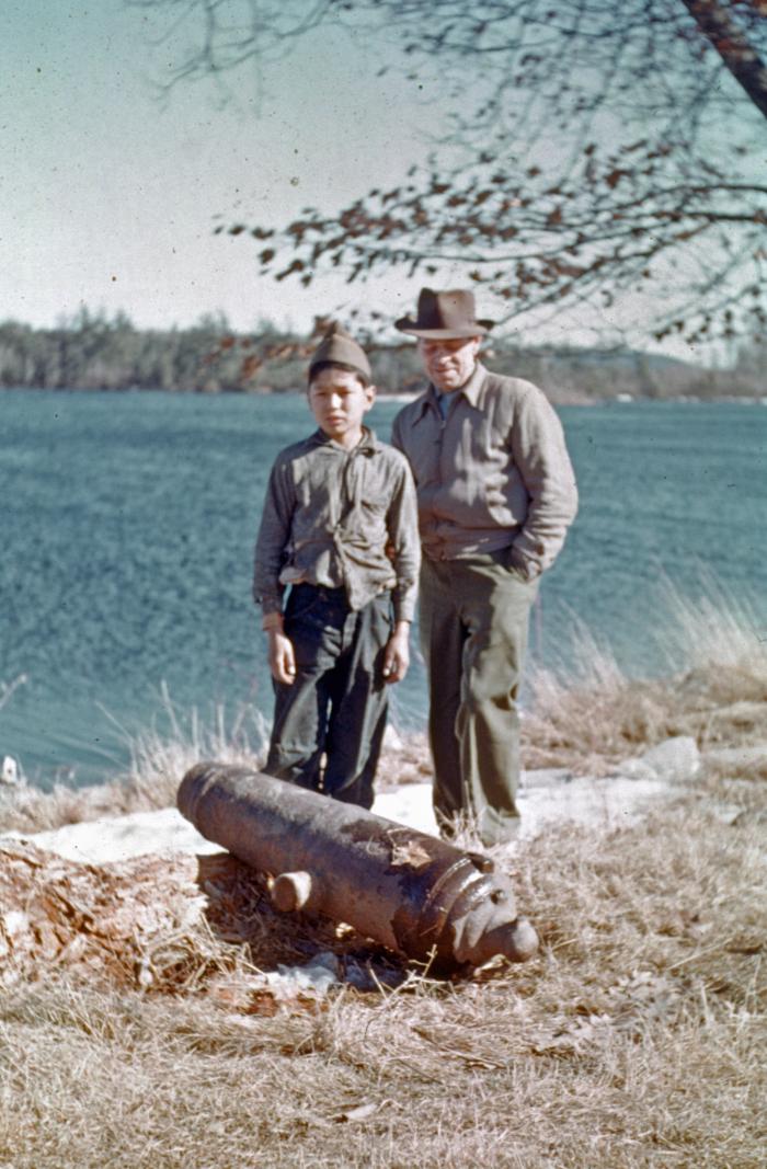 David Tomah (left, grandson of Sabattis Tomah) and Maliseet linguist Peter L. Paul (right, of Woodstock reserve, New Brunswick, a well-known visitor), standing next to the community's Revolutionary War cannon, circa 1950, Peter Dana Point, Indian Township, Maine, photograph and copyright by Nicholas N. Smith,  Courtesy of Nicholas N. Smith.